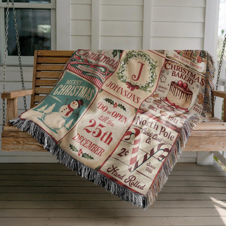 May include: A woven throw blanket featuring a grid of Christmas-themed illustrations including a snowman, a wreath with the letter J, a cake labeled Christmas Bakery, and candy canes with text reading Do not open till the 25th December.