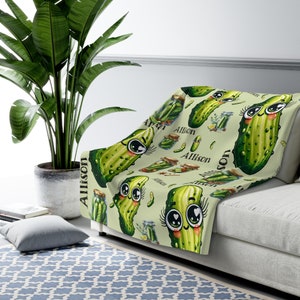 May include: A soft, green fleece throw blanket with a repeating pattern of cartoon pickles with big eyes and the name "Allison" printed throughout.