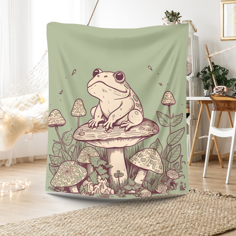 May include: A green tapestry featuring a cartoon frog sitting on a mushroom with other mushrooms and foliage surrounding it.
