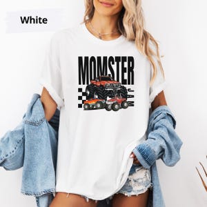 May include: White t-shirt with a black graphic of a monster truck and the text "MOMSTER JAM".