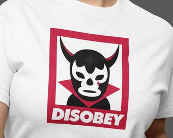 May include: White t-shirt with a red square graphic featuring a black and white luchador mask with a red drop of blood. The text "DISOBEY" is printed in white letters below the mask.