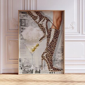 Op de afbeelding: Een digitale kunstprint met een paar laarzen met luipaardprint die in een martini-glas met olijven stappen. De achtergrond is een collage van krantenknipsels.