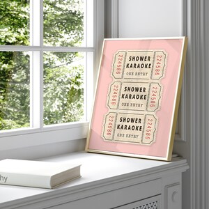 May include: Three vintage-style tickets with the text "Shower Karaoke" and the number "224586" printed on each. The tickets are on a pink background with a gold frame.