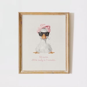 Könnte beinhalten: Gerahmter Druck mit einer Aquarellillustration einer weißen Ente mit Sonnenbrille und einem rosa Haarband. Der Text lautet: „Na klar, ich bin in 5 Minuten fertig...“