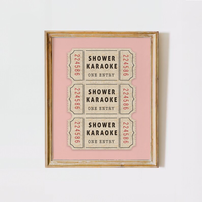 May include: Three vintage-style tickets with the text "Shower Karaoke" and "One Entry" printed on them. The tickets are brown with black text and red numbers. The tickets are framed on a pink background.