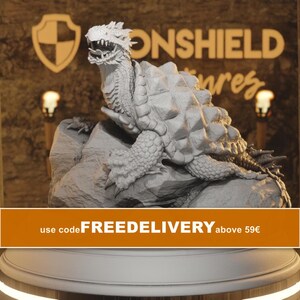 May include: A light gray, unpainted resin miniature of a dragon turtle standing on a rocky base. The creature features a detailed, spiked shell, textured scales on its limbs, and an open mouth with visible teeth, captured in a static pose.