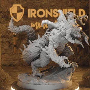 Op de afbeelding: Een gedetailleerd, grijs drakenbeeldje met scherpe klauwen, hoorns en getextureerde schubben. De sculptuur is dynamisch geposeerd, met het Ironsheild-logo zichtbaar op de achtergrond. De draak is gemonteerd op een cirkelvormige basis.