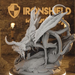 Peut inclure: Modèle imprimé en 3D gris détaillé d'un dragon avec des ailes déployées, perché sur une base rocheuse. Le dragon a une longue queue et des griffes acérées.