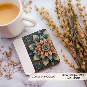 Op de afbeelding: Een witte vierkante onderzetter mockup met een kleurrijk mandala-ontwerp in tinten groen, blauw, oranje en rood. De onderzetter ligt op een wit oppervlak met gedroogde bloemen.