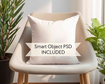 May include: A white pillow sits on a beige chair with wooden legs. The pillow is a smart object, meaning you can easily add your own design to it. The text "Smart Object PSD INCLUDED" is displayed on the pillow.