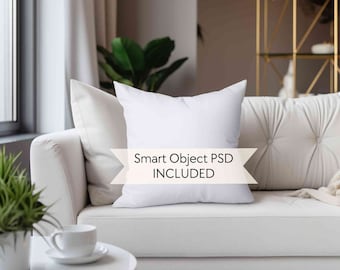 May include: White throw pillow mockup on a white couch with a white coffee table and a green plant. The pillow has a white background with the text "Smart Object PSD INCLUDED" in black.