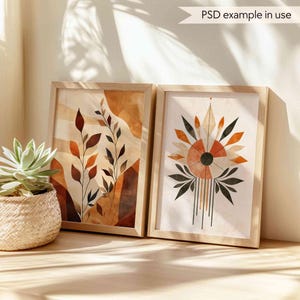 May include: Two framed abstract art prints with a boho aesthetic. The print on the left features a brown, orange, and white abstract design with leaves. The print on the right features a geometric design with a black circle in the center and brown, orange, and white accents.