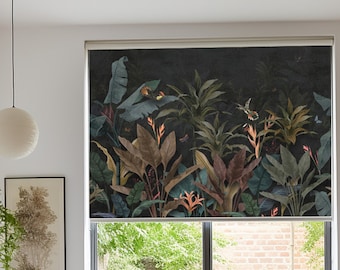 May include: A bedroom with a white bed, a white chair, and a window with a black roller shade featuring a tropical print of green and red plants and birds.