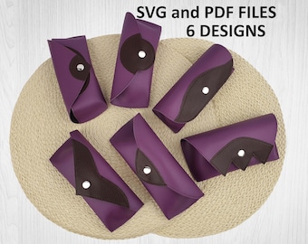 May include: Six purple and brown eyeglass cases with silver snap closures are arranged on a woven mat. The cases have a leather-like appearance and feature various brown accent shapes. Text at the top reads "SVG and PDF FILES 6 DESIGNS."