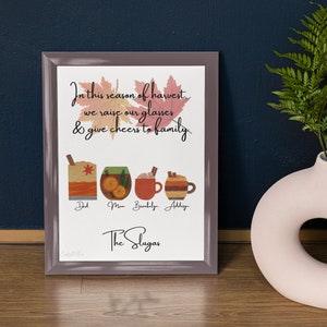 May include: A framed print with a fall-themed design. The print features a quote about raising a glass to family in the season of harvest, along with illustrations of four different drinks. The names "Dad", "Mom", "Brooklyn", and "Addy" are written below the drinks. The text "The Slugas" is at the bottom of the print.
