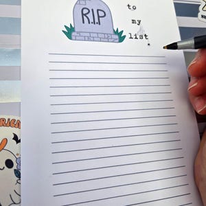 Pode incluir: Um bloco de notas pautado com uma ilustra&ccedil;&atilde;o de l&aacute;pide que diz "R.I.P." e as palavras "to my list". Uma m&atilde;o segura uma caneta, pronta para escrever na p&aacute;gina. O bloco de notas tem um tema de Halloween.