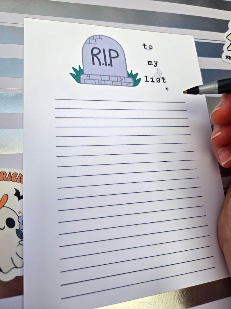 Pode incluir: Um bloco de notas pautado com uma ilustra&ccedil;&atilde;o de l&aacute;pide que diz "R.I.P." e as palavras "to my list". Uma m&atilde;o segura uma caneta, pronta para escrever na p&aacute;gina. O bloco de notas tem um tema de Halloween.
