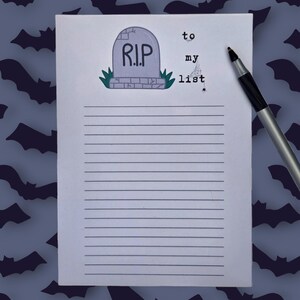 Pode incluir: Um bloco de notas pautado com uma ilustra&ccedil;&atilde;o de l&aacute;pide com a inscri&ccedil;&atilde;o "R.I.P." e as palavras "to my list". Uma caneta preta e prateada est&aacute; &agrave; direita. O fundo &eacute; azul escuro com silhuetas de morcegos.