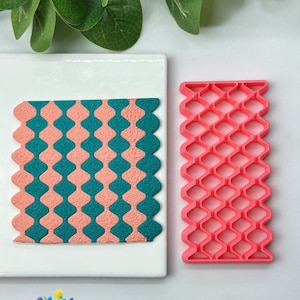 May include: A pink and teal patterned fondant or gum paste design created using a pink plastic embossing tool. The tool has a repeating diamond pattern. The number 811 is visible in the image.