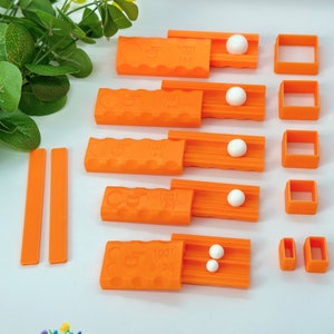 May include: Set of five orange plastic tools for making polymer clay beads. Each tool has a different size opening and a groove for rolling the clay. The tools are labelled with the number 1001 and the size of the opening. There are also two orange plastic strips.