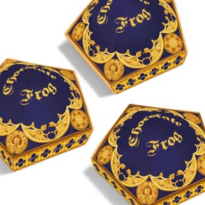 May include: Three hexagonal boxes with navy blue lids and gold ornate designs. The lids feature the words "Chocolate Frog" in gold script. The boxes have gold trim and are set against a white background.