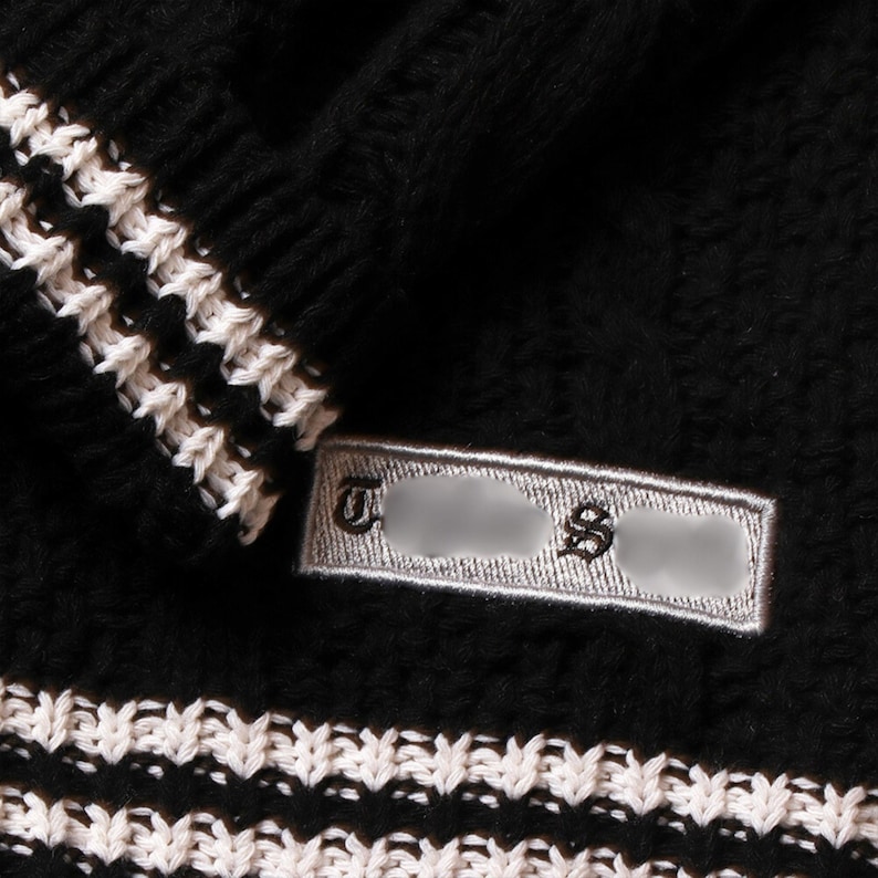 May include: Black knitted sweater with white trim and a small white label that says "T.S." in black lettering.