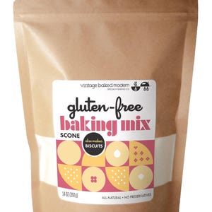 May include: A brown paper bag of gluten-free baking mix. The label features the text "gluten-free baking mix" in pink and white, with the words "scone" and "also makes biscuits" below. The bag contains 14 oz (397g) of mix.