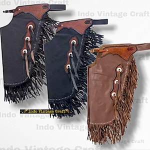 May include: Three leather chaps in black and brown, with fringe along the sides and bottom. The chaps have decorative stitching, metal accents, and a belt-style waist. The text "Indo Vintage Craft" is visible.