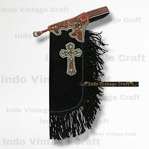 May include: Black suede chaps with a decorative cross and fringe. The chaps feature turquoise and silver embellishments and a brown leather belt. The text "Indo Vintage Craft" is visible.