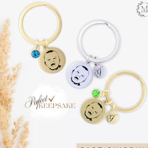 May include: Two gold and silver keychains with a photo charm of a baby. The charms are attached to a keyring with a small crystal. The text "Perfect Keepsake" is written in cursive on a white background. The text "Fast Shipping" is written in black on a white background.