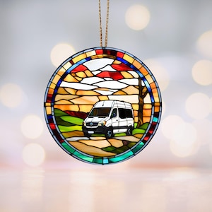 May include: A round stained glass ornament depicting a white van driving through a colourful landscape with red, orange, yellow, green, blue, and purple hues. The van is driving on a winding road with a tree on the right side of the image.