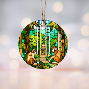 Puede incluir: Un adorno de vidrio tintado con dos monos sentados en un entorno de selva. Los monos son marrones y amarillos, y la selva es verde y azul. Hay un pequeño templo en el fondo.