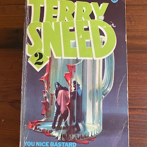Może przedstawiać: Okładka książki w miękkiej oprawie z zielono-żółtym tytułem "Terry Sneed 2" i tekstem "You Nice Bastard" oraz "A novel by G.F. Newman". Okładka przedstawia rozbitą szklaną filiżankę z krwią kapiącą z niej i trzema postaciami w środku.