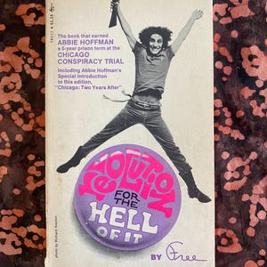 Puede incluir: Una portada de libro con una foto de un hombre saltando en el aire con los brazos en alto. El título del libro es "Revolution for the Hell of It" de Abbie Hoffman. La portada es blanca con texto negro y un círculo morado con texto rosa.