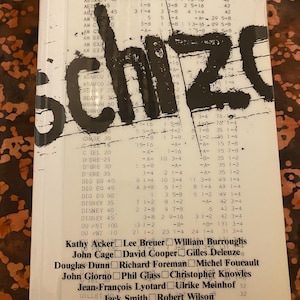 Peut inclure: Couverture de livre vintage pour "Schizo", une publication Semiotext(e) de 1978. La couverture présente des lettres noires en gras et une liste de noms, dont Kathy Acker et William Burroughs, sur un fond de texte imprimé.