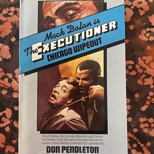 Pode incluir: Livro de bolso vintage intitulado "The Executioner: Chicago Wipeout" de Don Pendleton. A capa apresenta uma ilustração dramática de dois homens, com o título em texto em negrito e estilizado. Publicação Corgi.