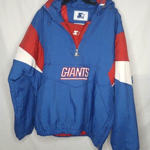 May include: A blue, red, and white pullover jacket featuring the word GIANTS in white lettering across the chest. The jacket has a half-zip closure with a Starter logo zipper pull, a hood, and a Starter brand label on the interior collar.