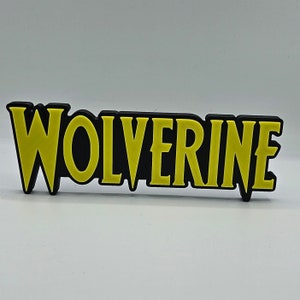 Puede incluir: Un letrero impreso en 3D negro y amarillo con la palabra "Wolverine" en letras negritas.