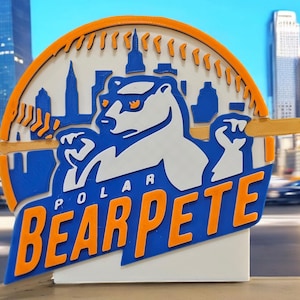 May include: A 3D printed blue and orange logo with a white polar bear wearing sunglasses and holding a baseball bat. The logo says "Polar Bearpete" and has a cityscape in the background.