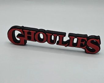 May include: Black and red 3D printed word "GHOULIES" with a bold, stylized font.