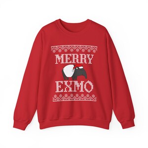 May include: A red sweatshirt with a festive design. The design includes the words "MERRY EXMO" in white, along with a cartoon tapir wearing a Santa hat. The design is in a sweater-like pattern.