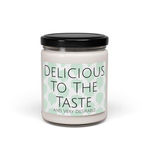 May include: A white candle in a glass jar with a black lid. The label features the text "DELICIOUS TO THE TASTE AND VERY DESIRABLE" over a pattern of light green leaves. The candle is a home decor item.