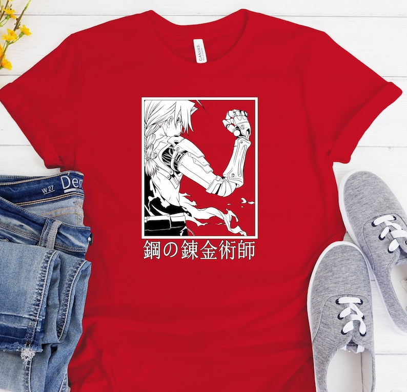 May include: Red t-shirt featuring a black and white graphic of an anime character with mechanical arm and the Japanese text "Fullmetal Alchemist" in a white rectangle. The shirt is paired with blue jeans and gray sneakers.