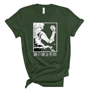 May include: Dark green t-shirt featuring a black and white anime-style illustration inside a white rectangle. The illustration depicts a character with mechanical arm and the Japanese text "Fullmetal Alchemist" below.