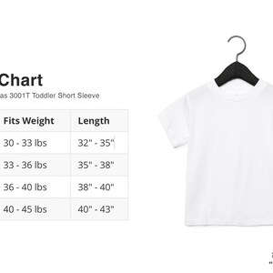 May include: A white toddler short sleeve t-shirt hanging on a black hanger. The image includes a size chart with measurements in inches and pounds for sizes 2T to 5T. The chart also includes the text "Bella + Canvas 3001T Toddler Short Sleeve".