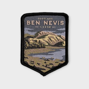 May include: A rectangular embroidered patch with a black border featuring a landscape of Ben Nevis in Scotland. The text reads SCOTLAND BEN NEVIS 1,343M. The design includes a mountain peak in shades of beige and brown, a blue sky, and a blue lake.