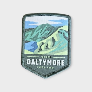 May include: A shield-shaped patch with a mountain scene in green, blue, and white. The text "GALTYMORE IRELAND" is at the bottom, with "918M" above. The patch has a dark green border, and the mountain is a prominent feature.