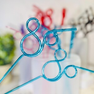 May include: Close-up of several decorative blue wire art pieces, each featuring a looping design. Other pieces in red, purple, and black are visible in the background, suggesting a party or event theme.