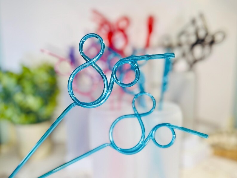May include: Close-up of several decorative blue wire art pieces, each featuring a looping design. Other pieces in red, purple, and black are visible in the background, suggesting a party or event theme.