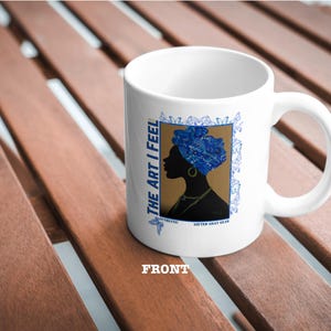 Peut inclure: Une tasse en céramique blanche avec un motif bleu et or représentant la silhouette d'une femme avec un turban bleu. Le texte "THE ART I FEEL" est imprimé sur la tasse.
